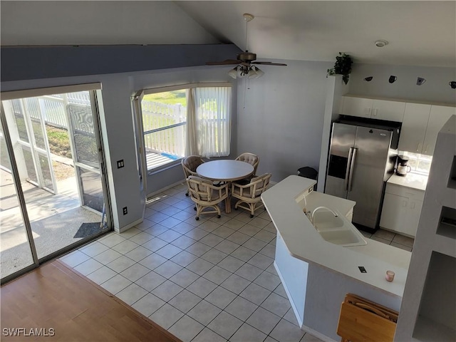 unfurnished dining area featuring ceiling fan, light tile patterned floors, sink, and vaulted ceiling