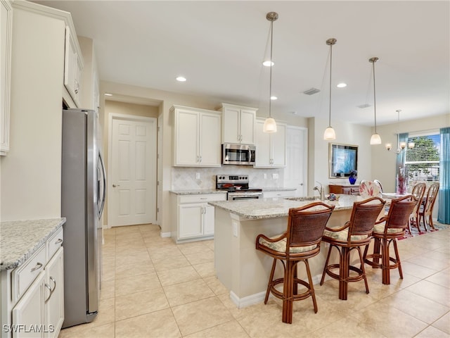 kitchen featuring stainless steel appliances, white cabinetry, and an island with sink