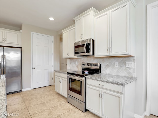 kitchen with light tile patterned floors, tasteful backsplash, light stone counters, white cabinetry, and stainless steel appliances