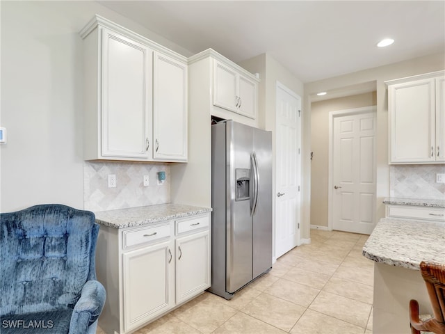 kitchen featuring stainless steel fridge, white cabinetry, backsplash, and light tile patterned floors