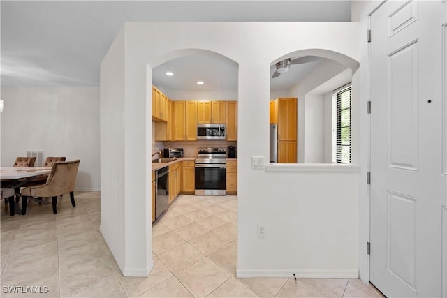 kitchen with tasteful backsplash, light brown cabinetry, light tile patterned floors, and stainless steel appliances