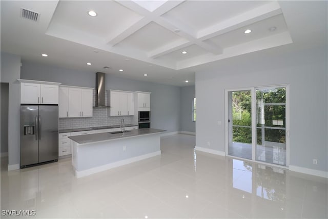 kitchen with coffered ceiling, white cabinets, a center island with sink, wall chimney exhaust hood, and appliances with stainless steel finishes