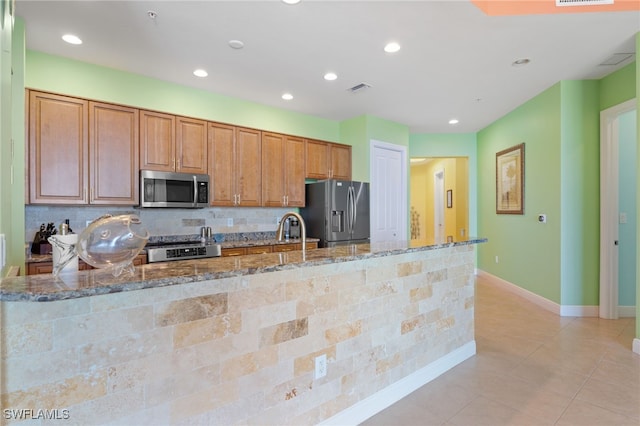 kitchen featuring stone counters, appliances with stainless steel finishes, light tile patterned floors, and sink