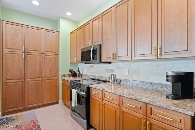 kitchen featuring light stone countertops, appliances with stainless steel finishes, decorative backsplash, and light tile patterned floors