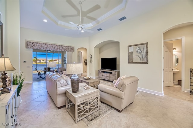 living room featuring ceiling fan, light tile patterned floors, crown molding, and a tray ceiling