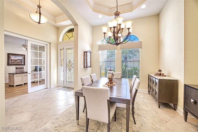 dining room with a tray ceiling, light tile patterned floors, ceiling fan with notable chandelier, and ornamental molding