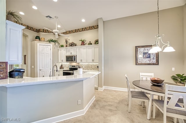 kitchen featuring white cabinets, pendant lighting, stainless steel appliances, and decorative backsplash