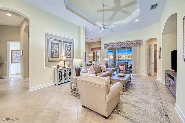 tiled living room with ceiling fan, a raised ceiling, and crown molding