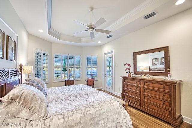 bedroom with ceiling fan, a tray ceiling, light hardwood / wood-style floors, access to outside, and ornamental molding