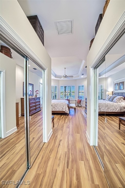 corridor with a raised ceiling and light hardwood / wood-style floors