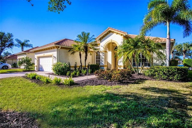 mediterranean / spanish-style home featuring a front yard and a garage