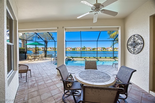 view of patio / terrace with glass enclosure, ceiling fan, and a water view