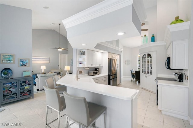 kitchen with a kitchen breakfast bar, kitchen peninsula, sink, appliances with stainless steel finishes, and white cabinetry