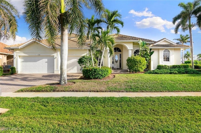 mediterranean / spanish home featuring a garage and a front lawn