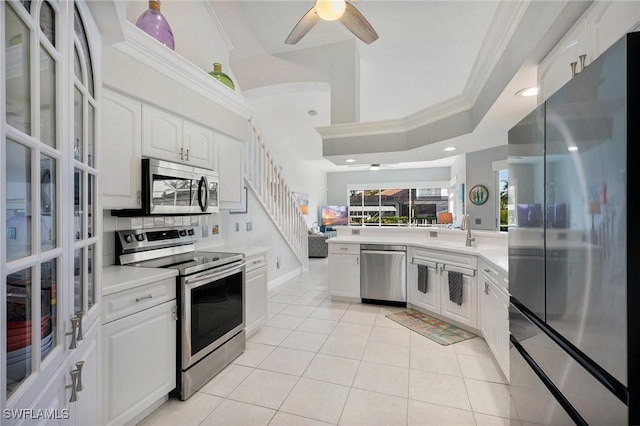 kitchen with white cabinets, light tile patterned flooring, crown molding, and appliances with stainless steel finishes