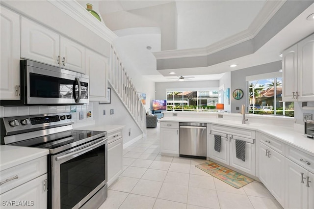 kitchen featuring stainless steel appliances, ceiling fan, crown molding, white cabinets, and light tile patterned flooring