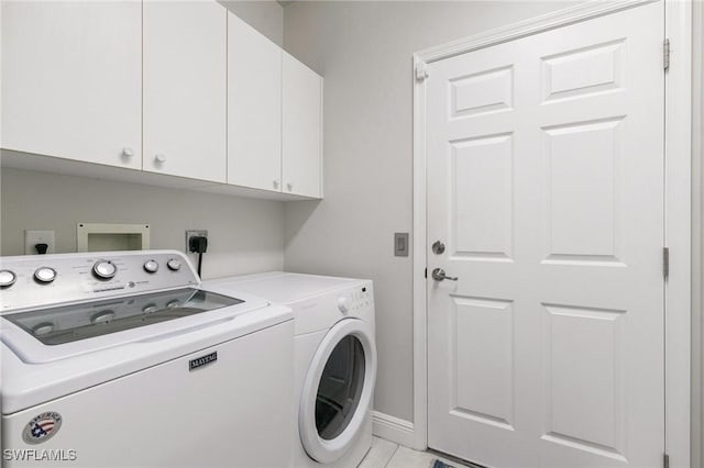 washroom with cabinets, light tile patterned floors, and washing machine and clothes dryer