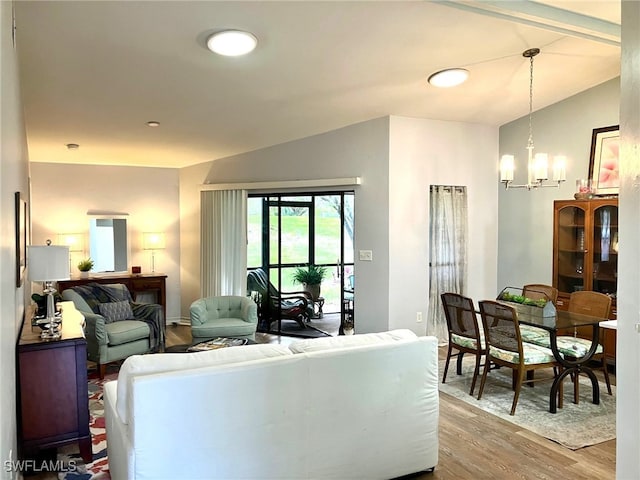 living room featuring lofted ceiling, an inviting chandelier, and hardwood / wood-style floors