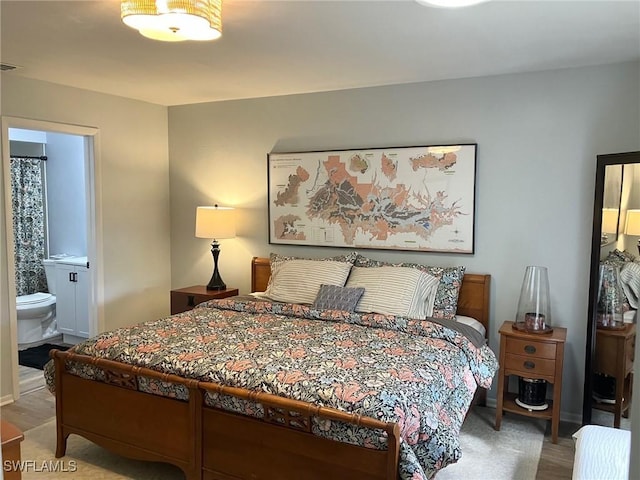 bedroom with hardwood / wood-style flooring and connected bathroom