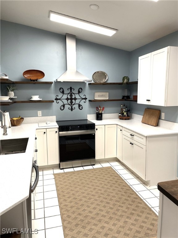 kitchen featuring range with electric stovetop, light tile patterned flooring, wall chimney range hood, white cabinets, and sink