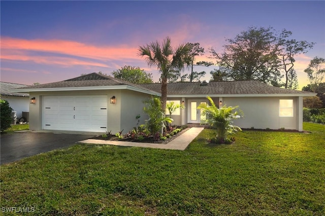 ranch-style home featuring a yard and a garage