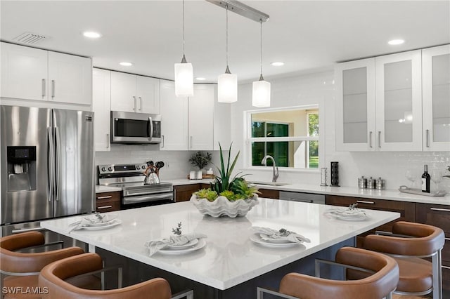 kitchen with a breakfast bar, appliances with stainless steel finishes, a center island, and white cabinets