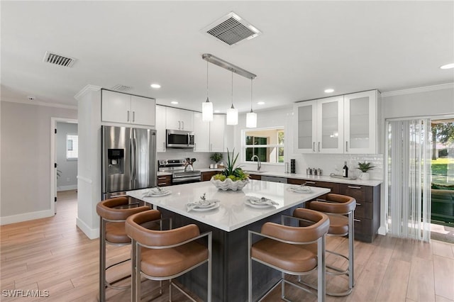 kitchen featuring sink, a center island, light hardwood / wood-style floors, white cabinets, and appliances with stainless steel finishes