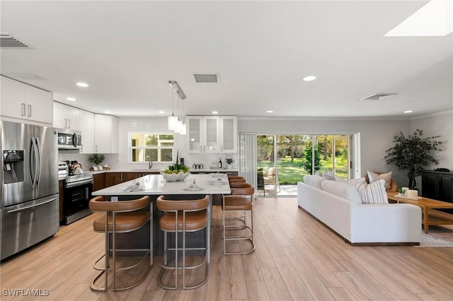 kitchen featuring hanging light fixtures, white cabinets, a healthy amount of sunlight, and appliances with stainless steel finishes