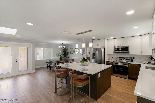 kitchen featuring appliances with stainless steel finishes, a breakfast bar, a center island, light hardwood / wood-style floors, and hanging light fixtures