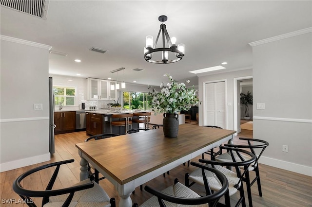 dining area with crown molding, light hardwood / wood-style floors, and a notable chandelier