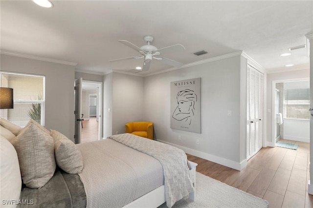 bedroom featuring multiple windows, ensuite bathroom, light hardwood / wood-style flooring, and ceiling fan