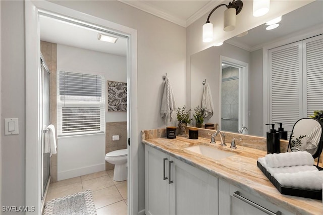 bathroom featuring vanity, a shower with door, tile patterned floors, crown molding, and toilet