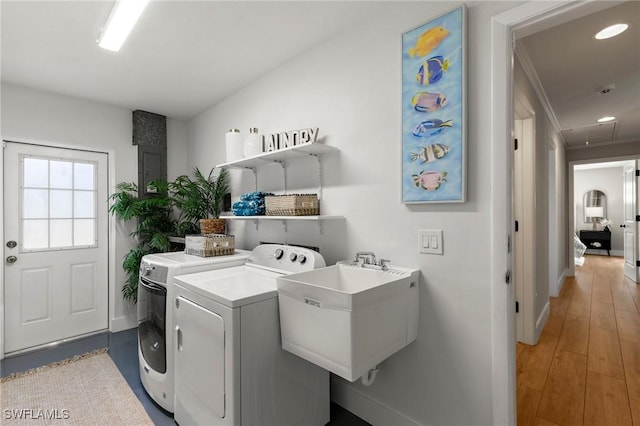 clothes washing area featuring washer and clothes dryer, light hardwood / wood-style flooring, and sink