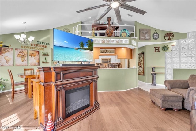 living room featuring ceiling fan with notable chandelier, vaulted ceiling, and light wood-type flooring