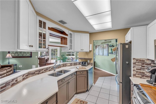 kitchen with white cabinets, light tile patterned floors, stainless steel appliances, and sink