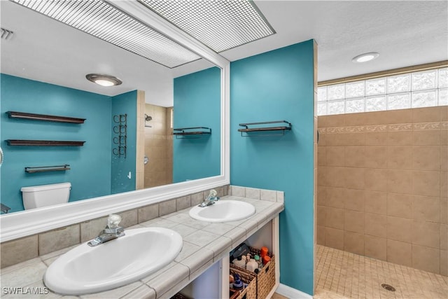 bathroom featuring a tile shower, vanity, and toilet