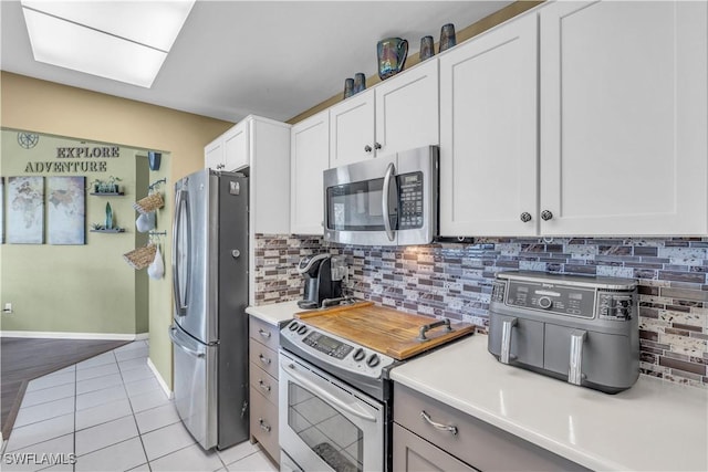 kitchen with white cabinets, light tile patterned floors, backsplash, and appliances with stainless steel finishes