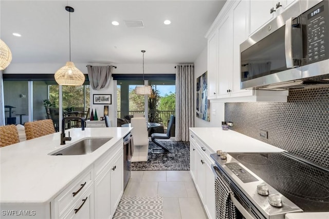 kitchen featuring sink, light tile patterned floors, pendant lighting, white cabinets, and appliances with stainless steel finishes