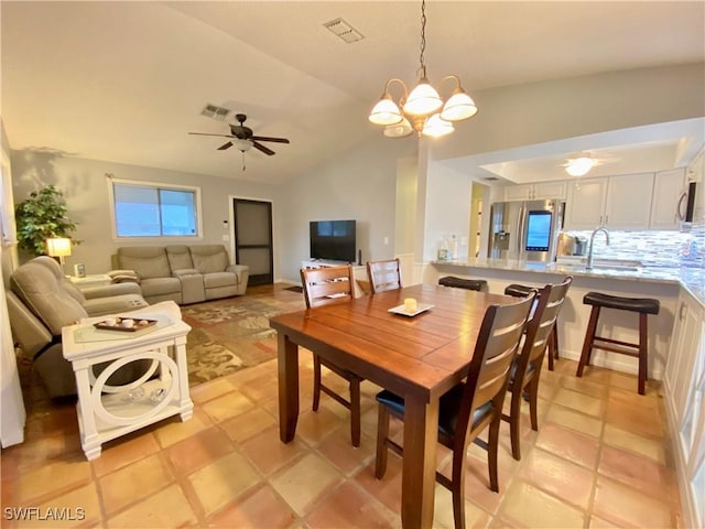 tiled dining room with vaulted ceiling, sink, and ceiling fan with notable chandelier