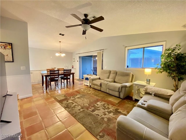 tiled living room featuring lofted ceiling, ceiling fan with notable chandelier, and a textured ceiling