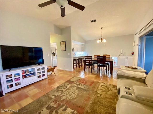 living room featuring ceiling fan with notable chandelier, vaulted ceiling, and tile patterned floors