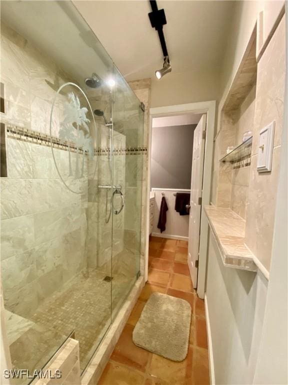 bathroom featuring a shower with door, tile patterned floors, and rail lighting