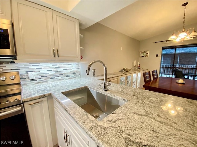 kitchen with pendant lighting, white cabinetry, sink, decorative backsplash, and range