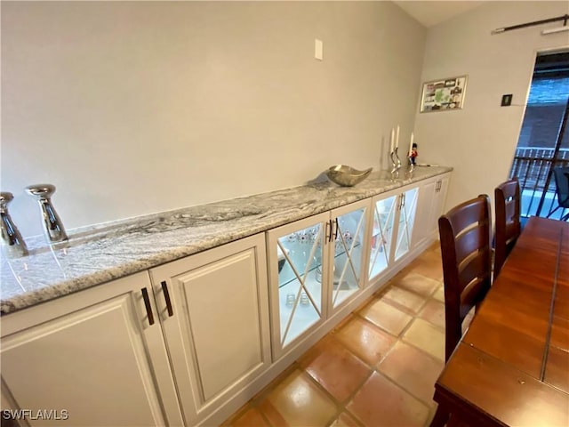 bar featuring white cabinetry, light stone countertops, and light tile patterned floors