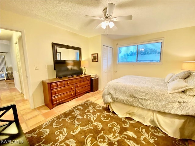 bedroom with tile patterned flooring, a textured ceiling, a closet, and ceiling fan