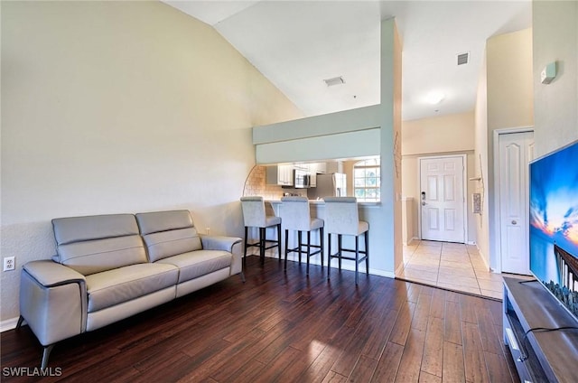 living room with wood-type flooring and high vaulted ceiling