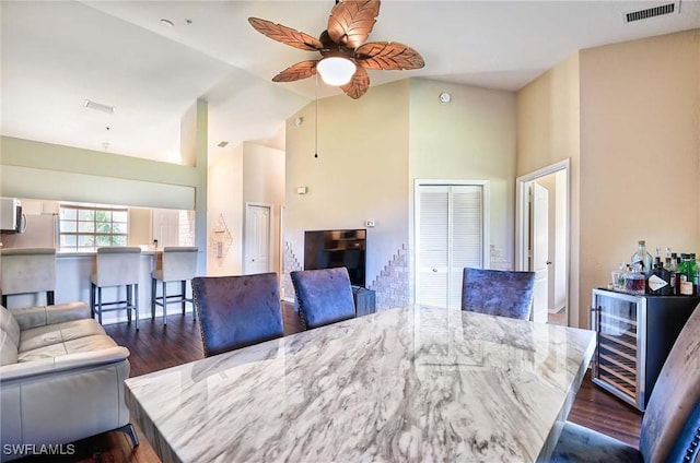 dining space with ceiling fan, dark wood-type flooring, wine cooler, and vaulted ceiling