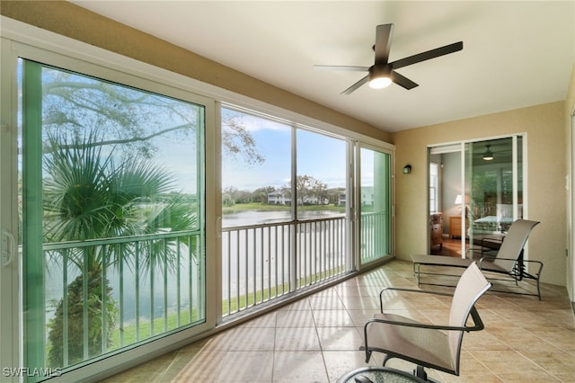 sunroom / solarium featuring a water view and ceiling fan