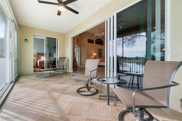 sunroom featuring ceiling fan and a water view