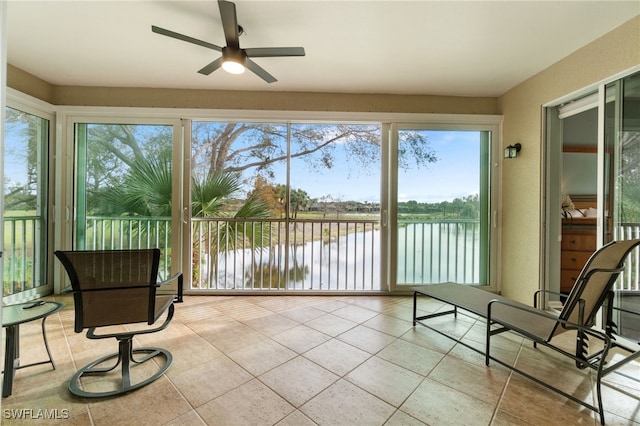 sunroom featuring ceiling fan, a water view, and a healthy amount of sunlight